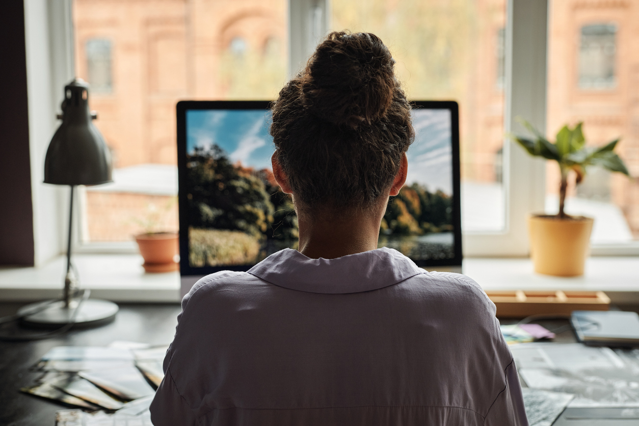 A web designer, working remotely, editing photos on her laptop