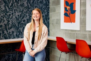 VP of Content, Natalie Nygren, smiles for the camera while standing in the corner of an office space discussing why a content audit matters.