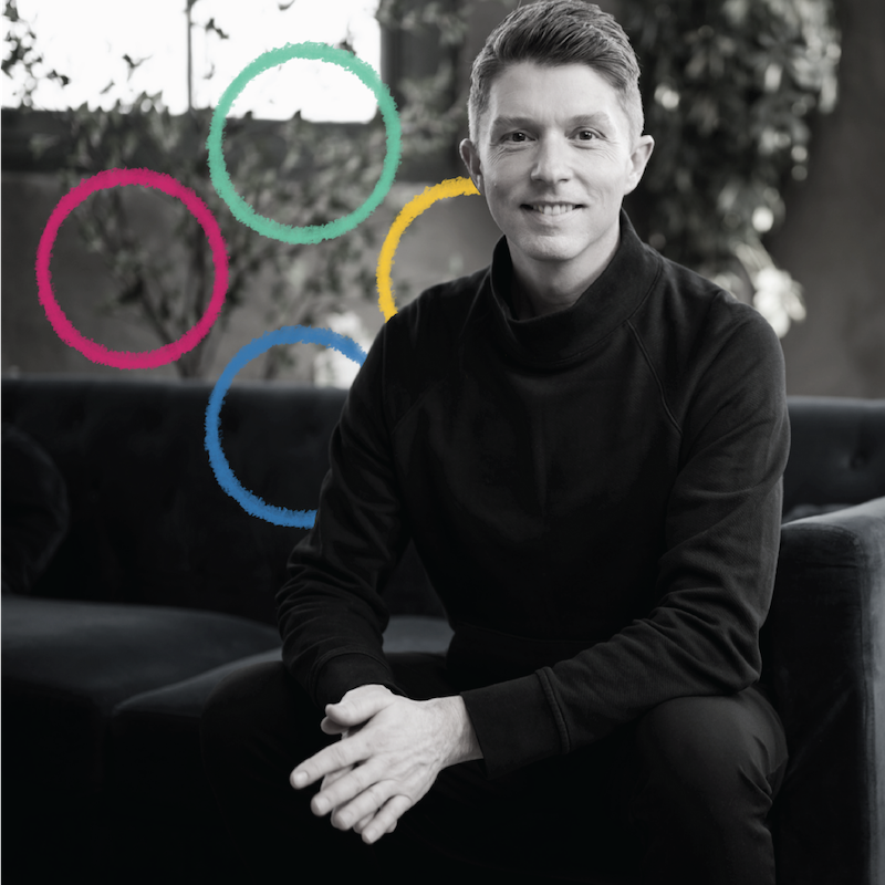 VP of Brand Strategy, Nathan Miller, is seated in a black and white photo, smiling at the camera with a colorful graphic treatment of circles behind him.