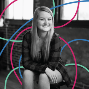 VP of Content and expert copywriter, Natalie Nygren, is photographed in black and white, seated in front of the camera and smiling. she is surrounded by teal, magenta, and blue lines, creating a colorful graphic effect.