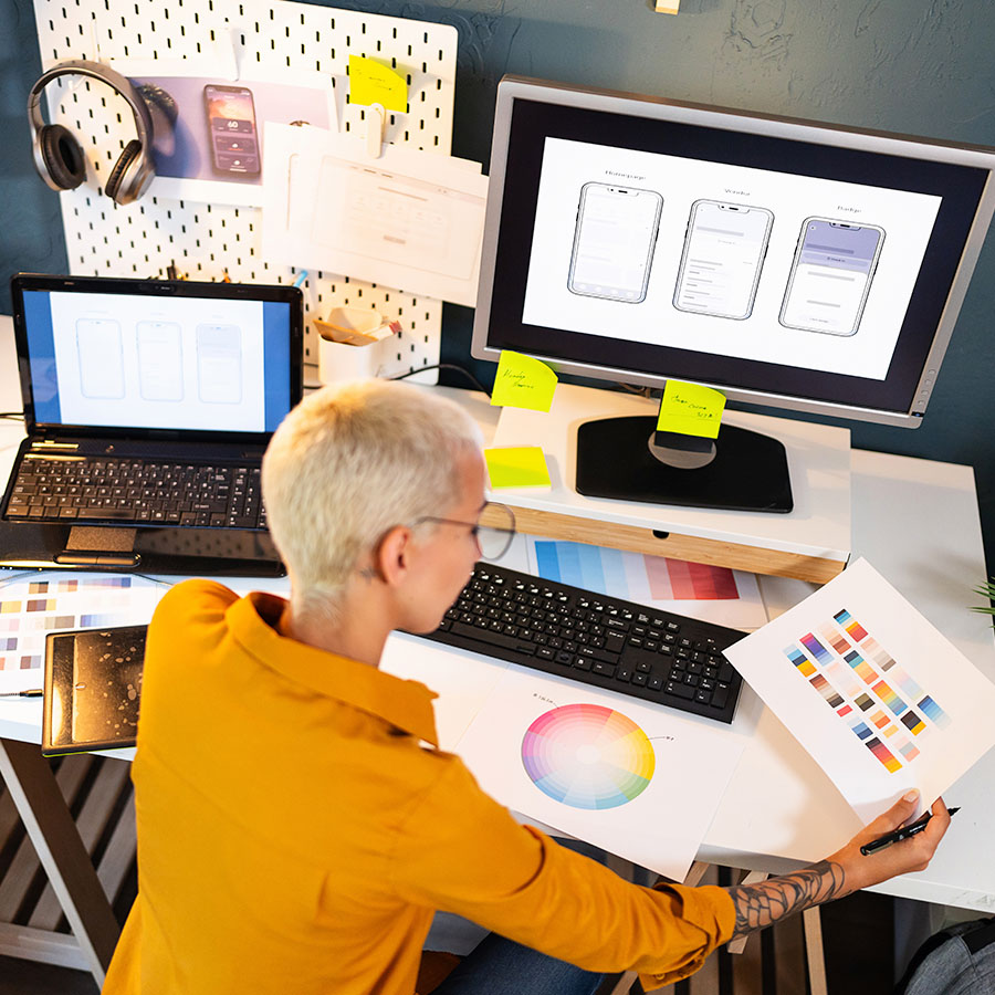 A graphic designer works on a brand color guide on their computer and desk