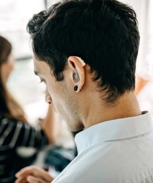 The back of a man's head with a hearing aid visible