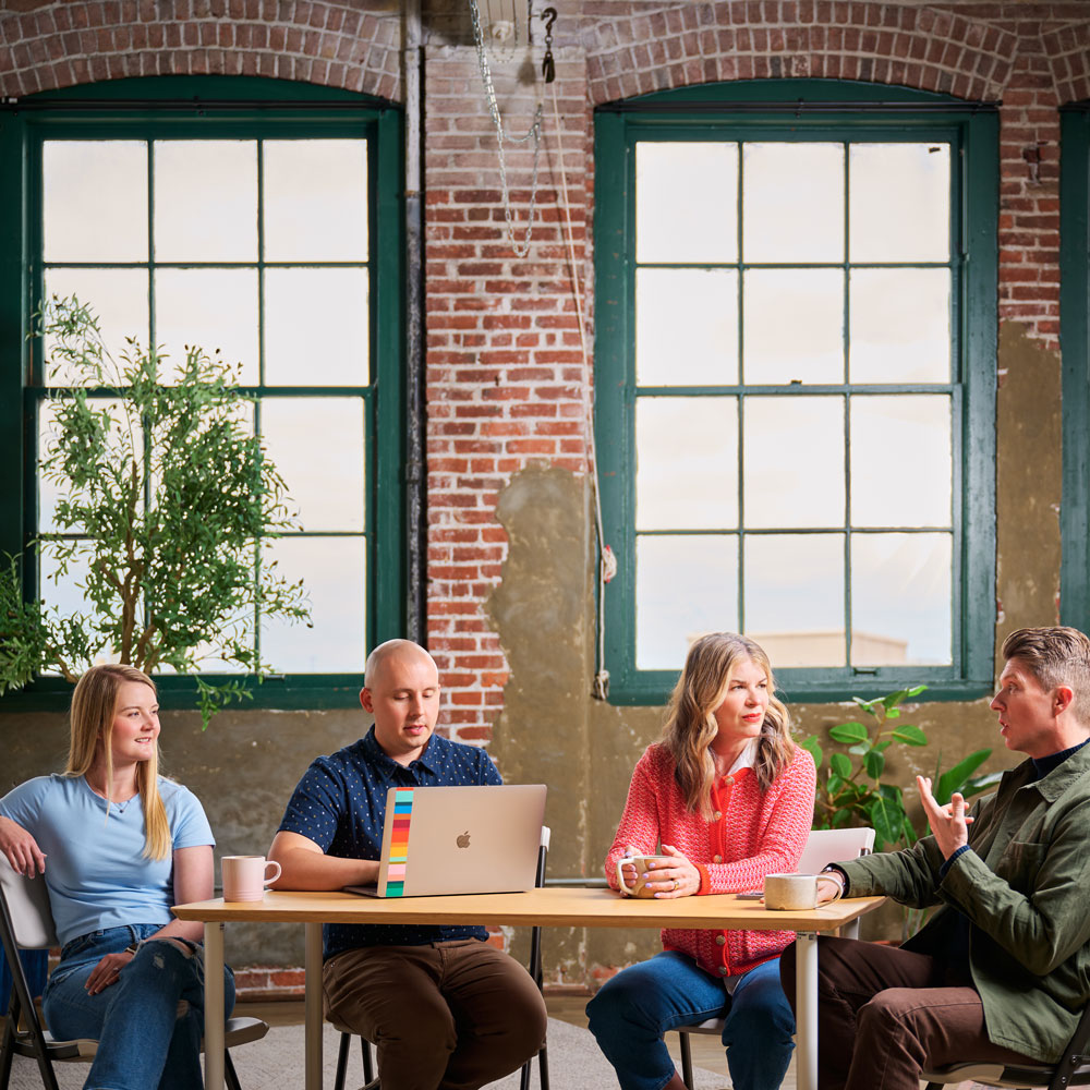 Members of the Formada team sitting around a table and talking marketing